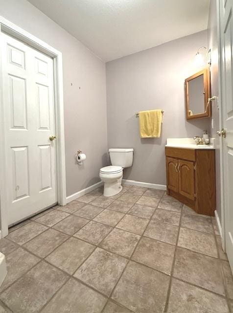 bathroom with toilet, baseboards, and vanity
