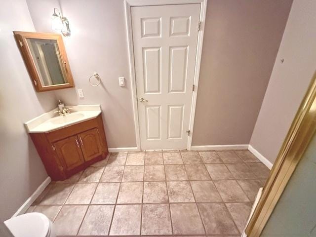 bathroom featuring toilet, tile patterned floors, baseboards, and vanity