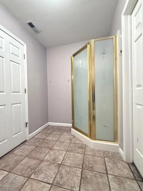 bathroom with baseboards, a shower stall, a textured ceiling, and visible vents