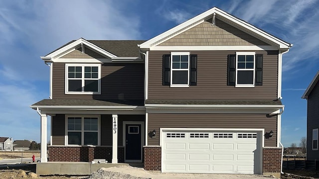 craftsman-style house with an attached garage, a porch, driveway, and brick siding