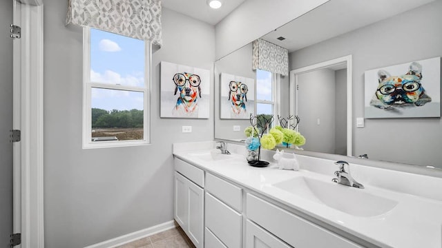bathroom with baseboards, a sink, tile patterned floors, and double vanity