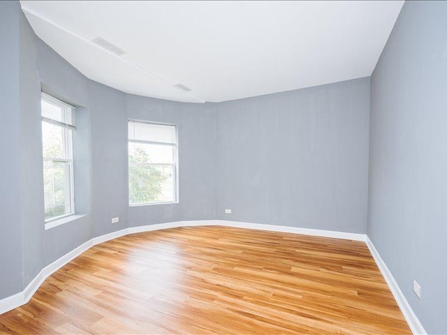 spare room with light wood-style floors, baseboards, and visible vents