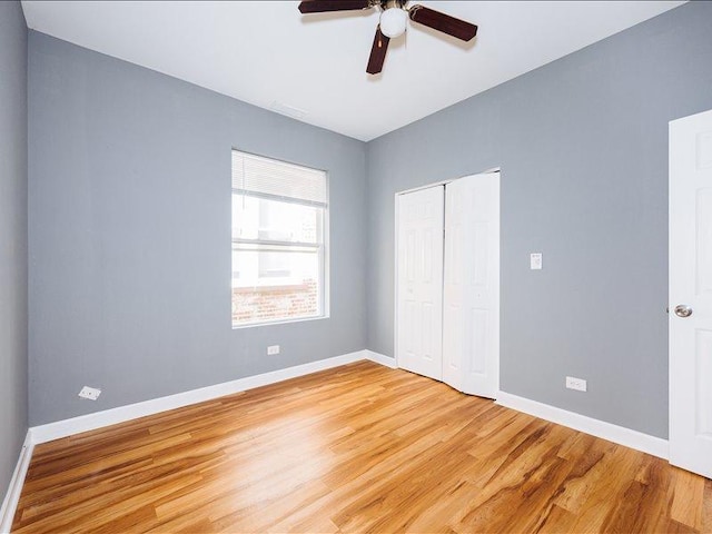 unfurnished bedroom with baseboards, ceiling fan, a closet, and light wood-style flooring