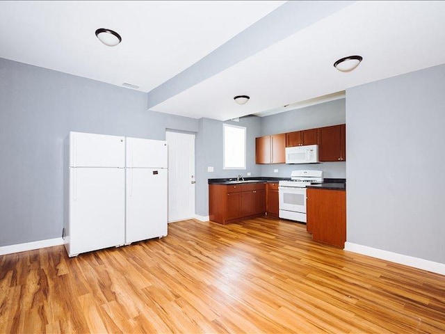 kitchen featuring white appliances, dark countertops, and baseboards