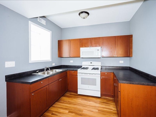 kitchen with white appliances, brown cabinets, a sink, and light wood-style floors