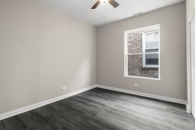 unfurnished room featuring baseboards, a ceiling fan, dark wood finished floors, and visible vents
