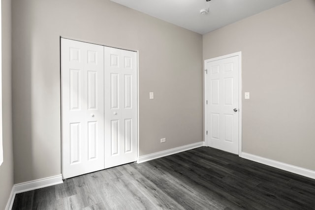 unfurnished bedroom featuring baseboards, a closet, and dark wood-style floors