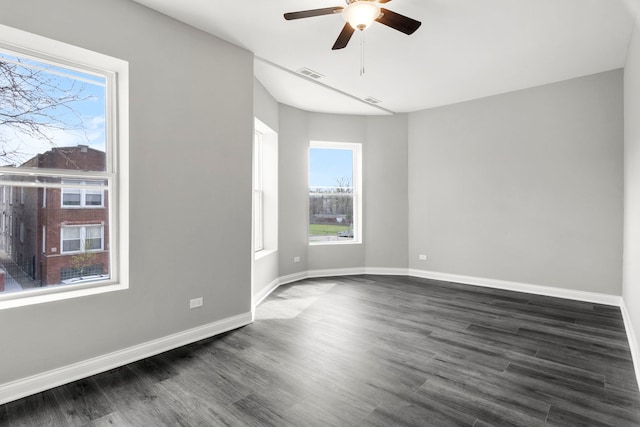 unfurnished room featuring visible vents, a ceiling fan, plenty of natural light, and dark wood-type flooring