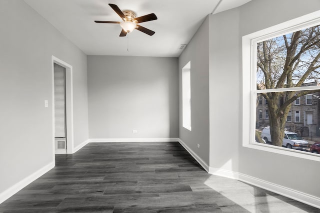 unfurnished room with ceiling fan, visible vents, dark wood-style floors, and baseboards