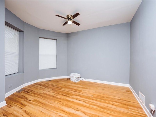 spare room with baseboards, a ceiling fan, wood finished floors, and visible vents