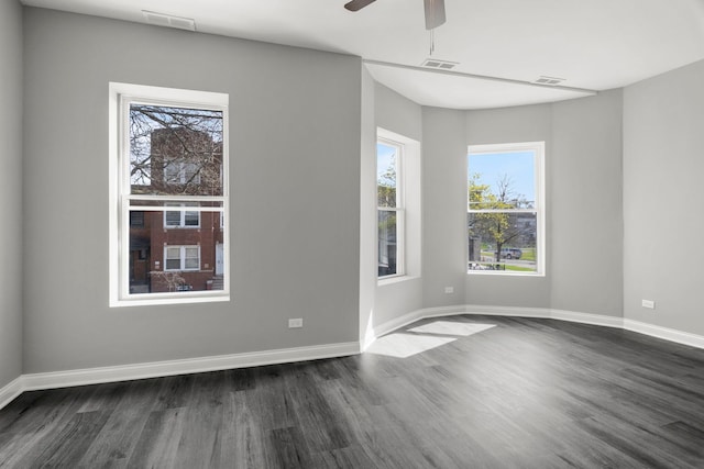 unfurnished room featuring dark wood-type flooring, ceiling fan, visible vents, and a wealth of natural light