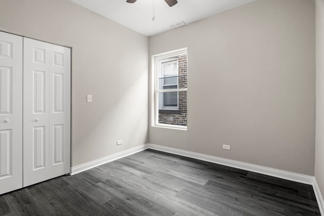 unfurnished bedroom with a ceiling fan, baseboards, dark wood-type flooring, visible vents, and a closet