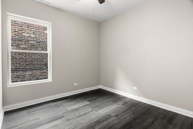 spare room featuring baseboards, ceiling fan, dark wood-style flooring, and visible vents