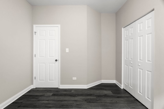 unfurnished bedroom with baseboards, a closet, and dark wood-style floors