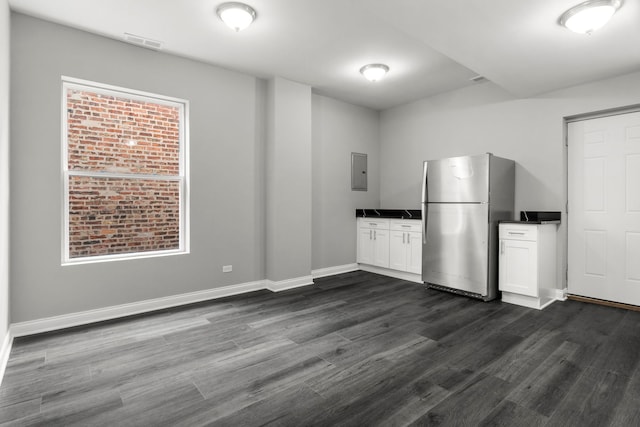 kitchen featuring electric panel, dark wood-style flooring, visible vents, dark countertops, and freestanding refrigerator