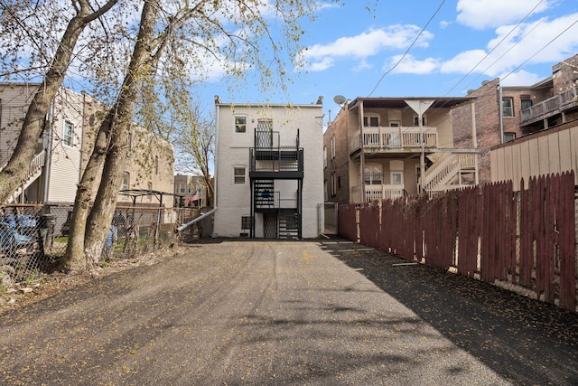 back of house featuring fence, stairs, and stucco siding