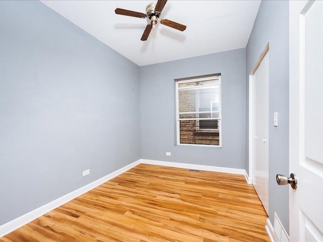 spare room with light wood-style floors, baseboards, ceiling fan, and visible vents