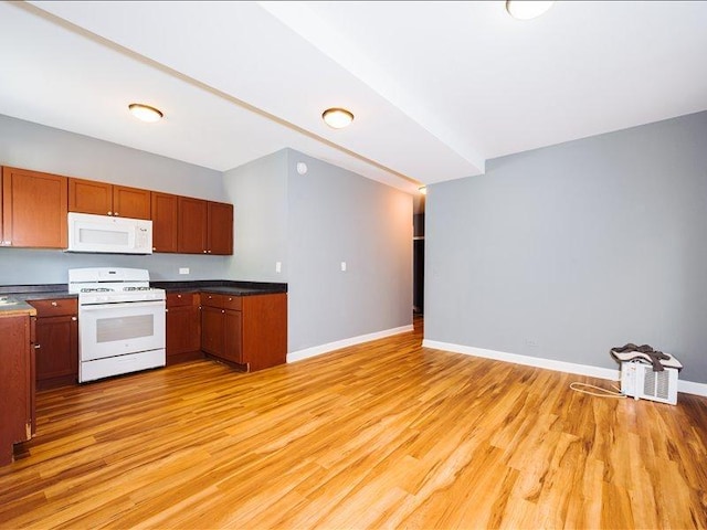 kitchen with dark countertops, brown cabinets, baseboards, white appliances, and light wood-style flooring