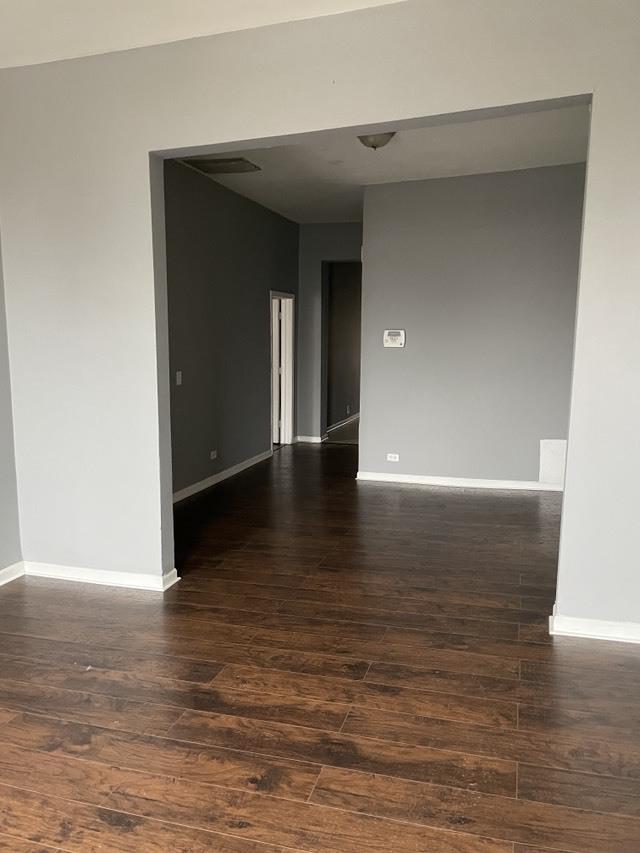 unfurnished room featuring baseboards and dark wood-style flooring