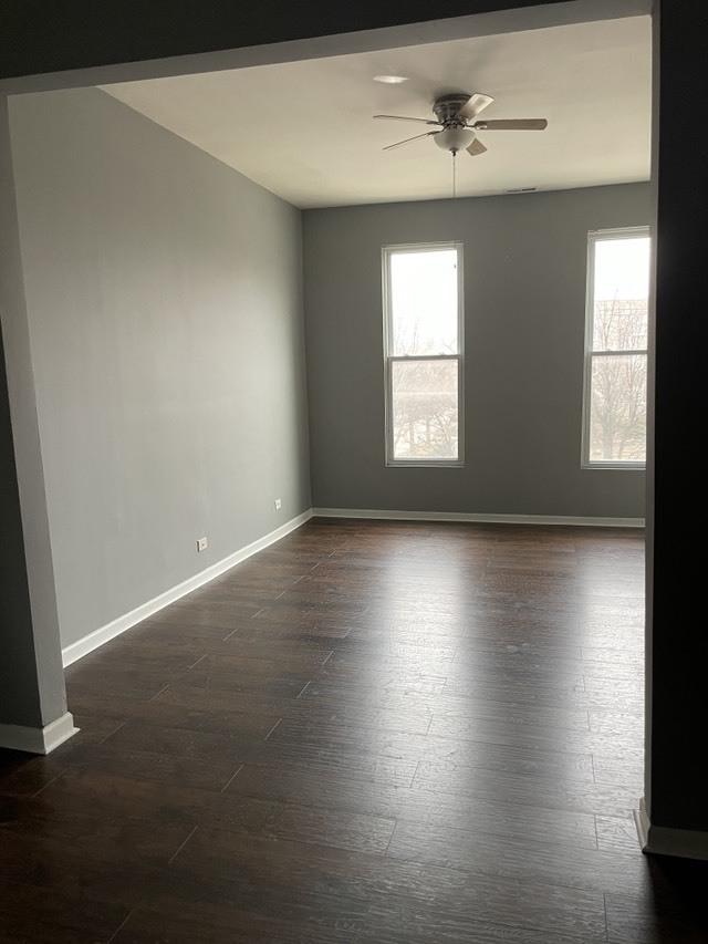 unfurnished room with baseboards, ceiling fan, and dark wood-style floors