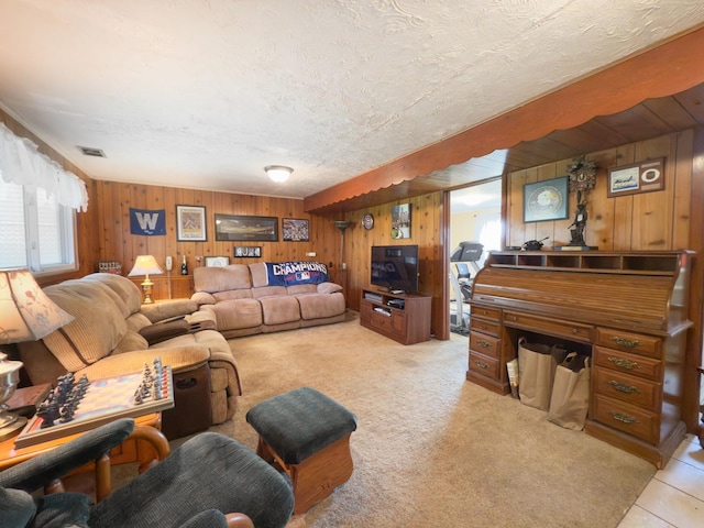 living area with light colored carpet, wood walls, visible vents, and a textured ceiling