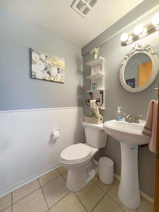 half bathroom featuring tile patterned floors, toilet, and visible vents