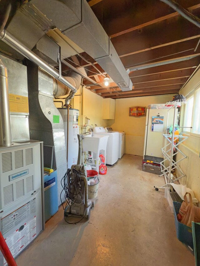 below grade area featuring heating unit, washing machine and dryer, a sink, freestanding refrigerator, and water heater