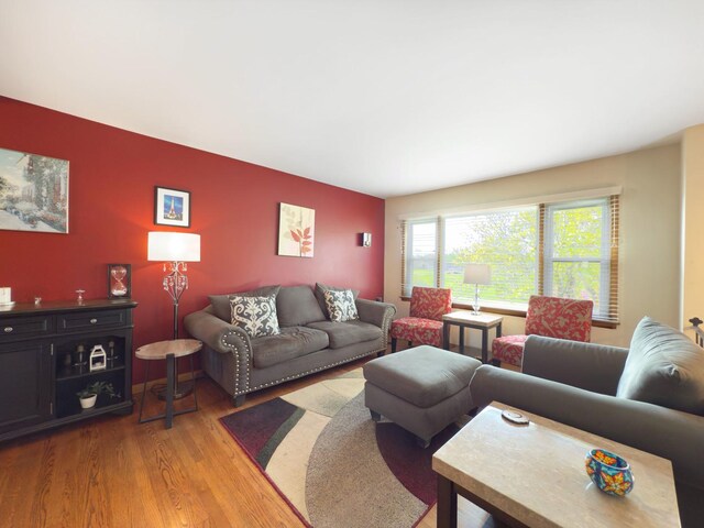 living area featuring light wood-style flooring and an accent wall
