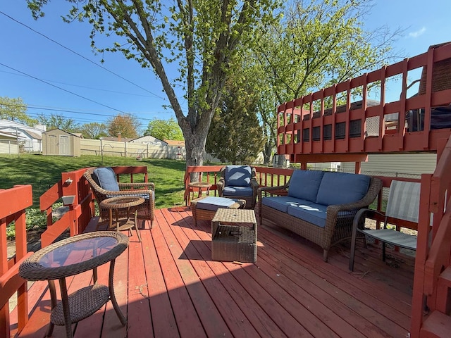 deck featuring outdoor lounge area, a yard, fence, and a storage unit