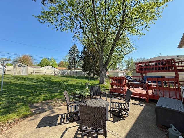 view of patio with fence, an outdoor structure, a storage unit, outdoor dining space, and a wooden deck