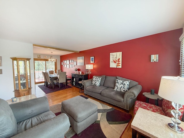 living area featuring a chandelier, wood finished floors, and an accent wall
