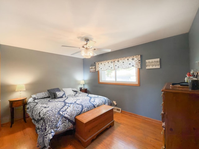 bedroom with ceiling fan, baseboards, visible vents, and wood finished floors