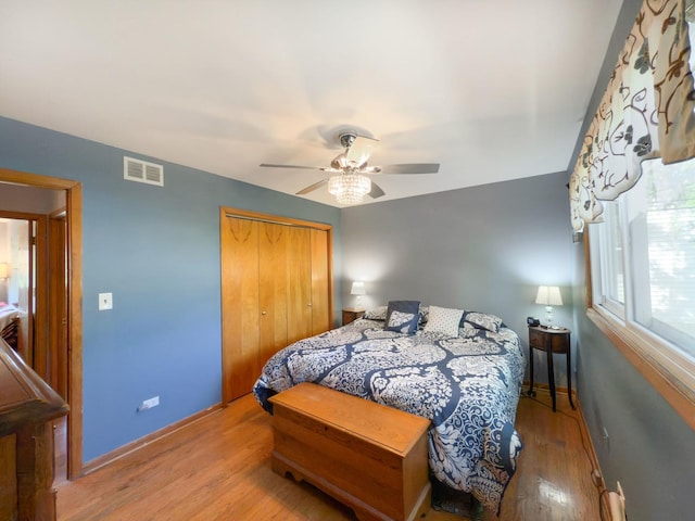 bedroom featuring wood finished floors, a ceiling fan, a closet, visible vents, and baseboards