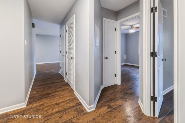 corridor featuring dark wood-style flooring and baseboards