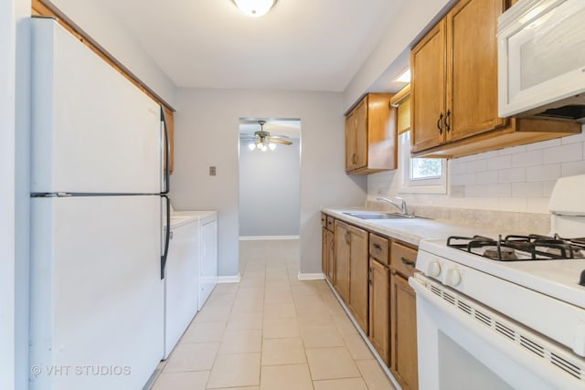 kitchen with white appliances, separate washer and dryer, brown cabinets, ceiling fan, and light countertops