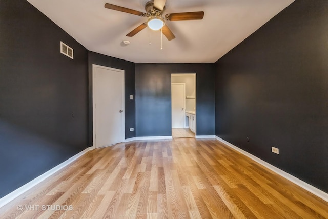 unfurnished bedroom featuring light wood-type flooring, ensuite bathroom, and ceiling fan