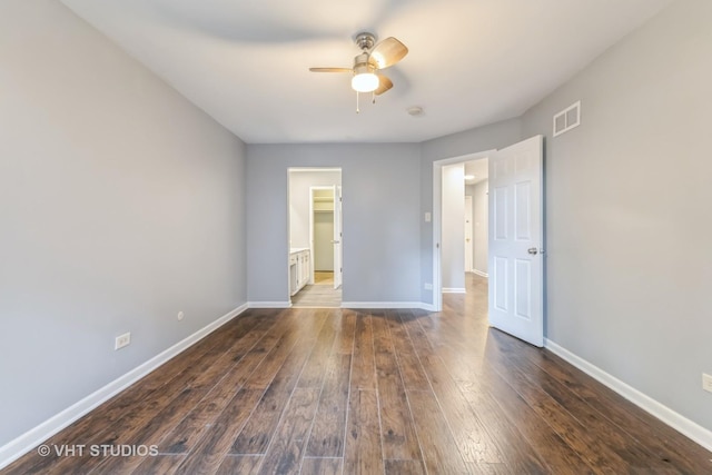 unfurnished bedroom with dark wood-type flooring, ceiling fan, and a spacious closet