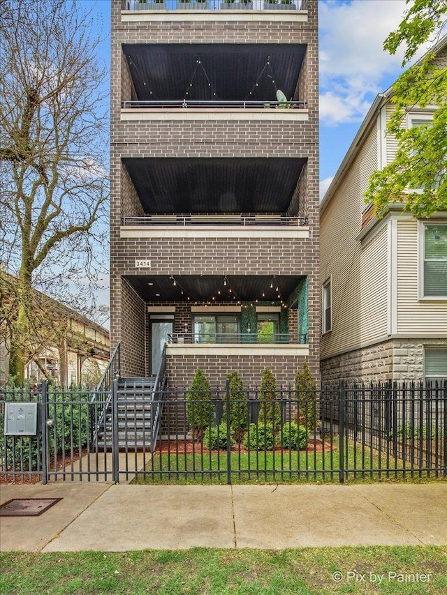 view of front facade featuring stairs, a fenced front yard, and brick siding