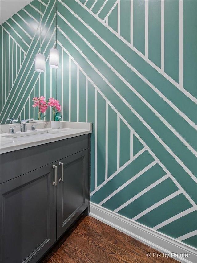 bathroom with a decorative wall, wood finished floors, and vanity