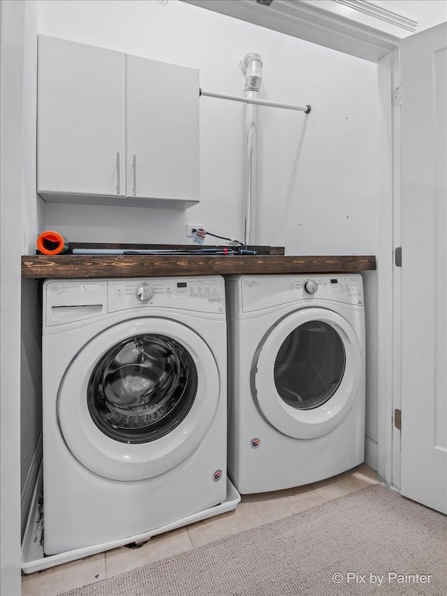 laundry room with light tile patterned floors, washing machine and dryer, and cabinet space