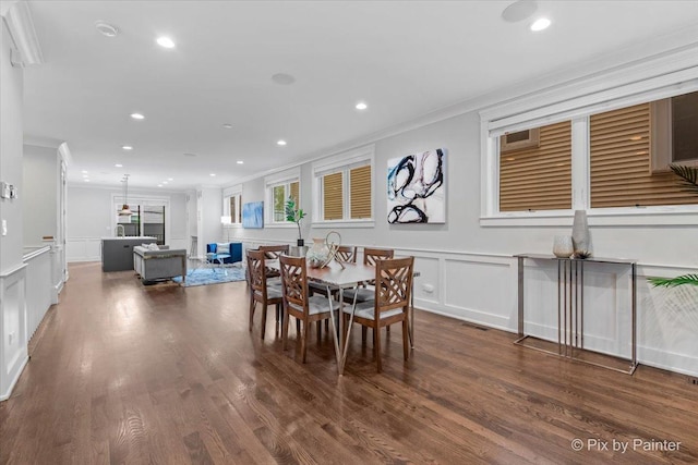 dining space with crown molding, recessed lighting, a decorative wall, and wood finished floors