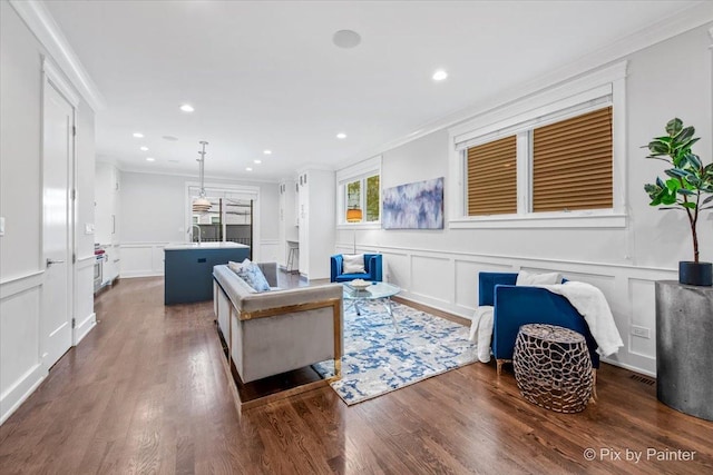 living room featuring dark wood-style flooring, recessed lighting, ornamental molding, and a decorative wall