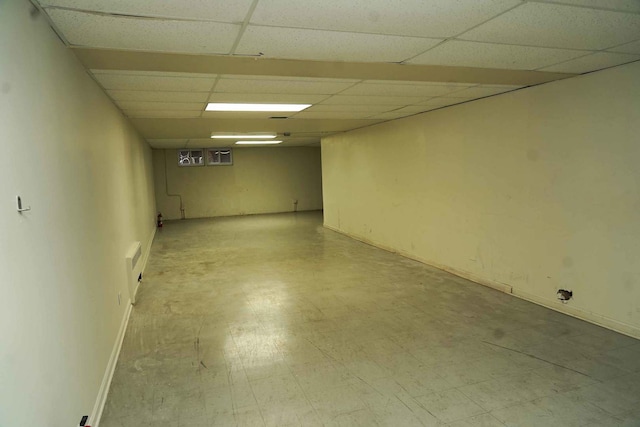 finished below grade area with tile patterned floors, baseboards, and a drop ceiling