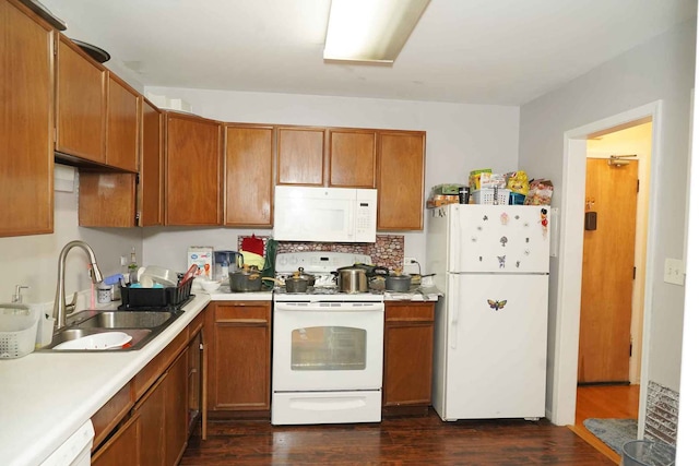 kitchen featuring a sink, white appliances, light countertops, brown cabinetry, and dark wood-type flooring