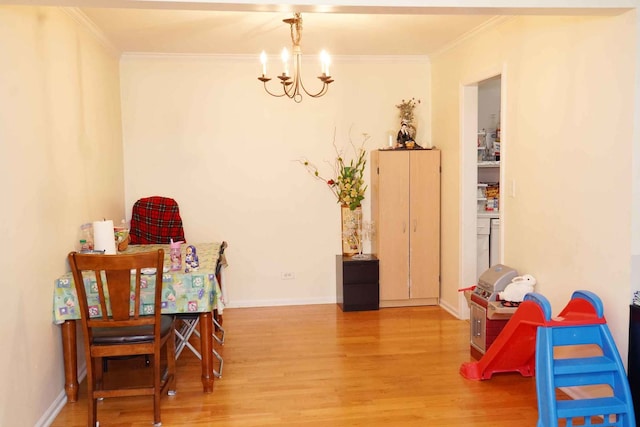 dining space featuring baseboards, a chandelier, ornamental molding, and wood finished floors