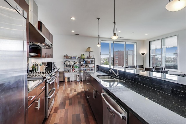 kitchen with dark wood-style flooring, modern cabinets, a sink, dark stone counters, and stainless steel appliances