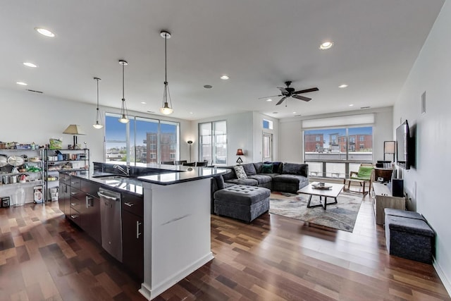 kitchen with a ceiling fan, dark countertops, dishwasher, a sink, and open floor plan
