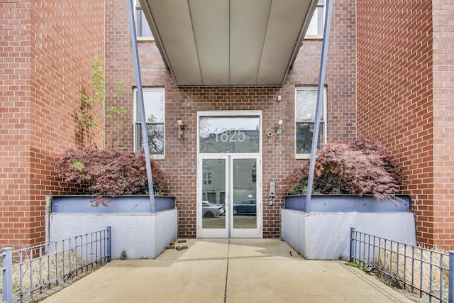 doorway to property featuring brick siding and fence