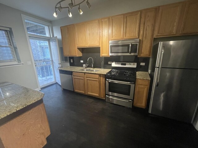 kitchen featuring appliances with stainless steel finishes, a sink, and light stone counters