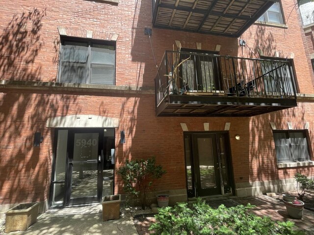 entrance to property featuring brick siding and a balcony